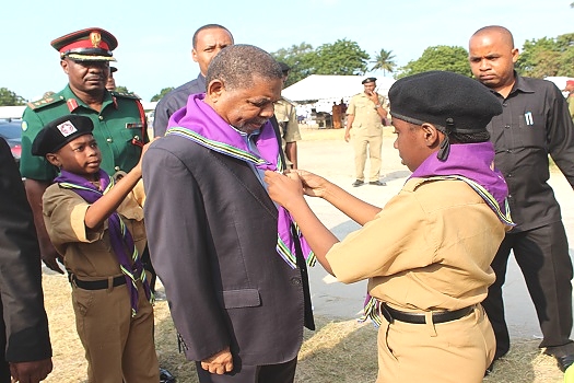 Rais wa ZAnzibar na Mwenyekiti wa Baraza la Mapinduzi Mhe. Dk Ali Mohamed Shein, akifungwa kiskafu na Vijana wa Skauti kushoto Halima Ali Makame na kulia Lutfia Juma Ali, baada ya kuwasili katika viwanja vya Mpira vya Maisara Suleiman Zanzibar kuhudhuria